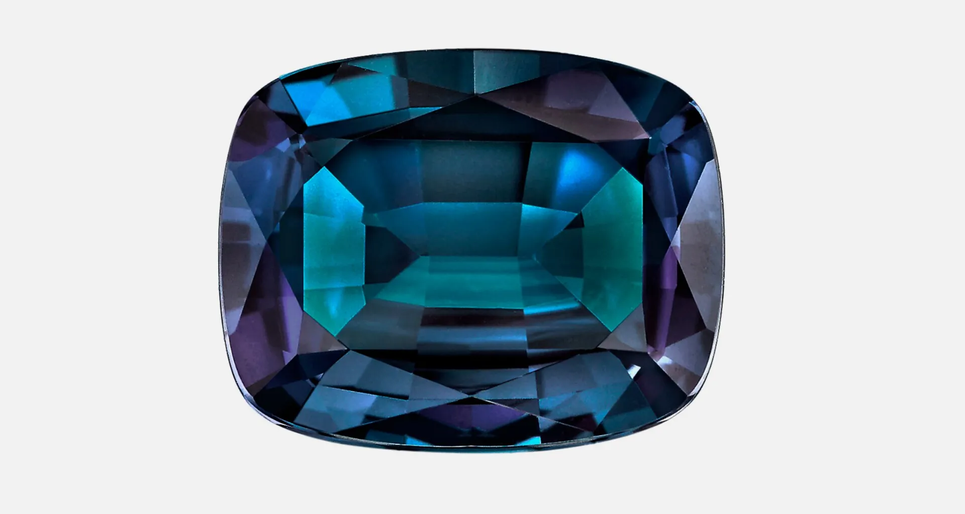 Rough alexandrite crystal alongside a faceted alexandrite showing its dramatic color change